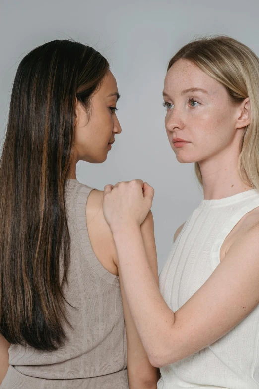 two girls facing each other in front of a white background