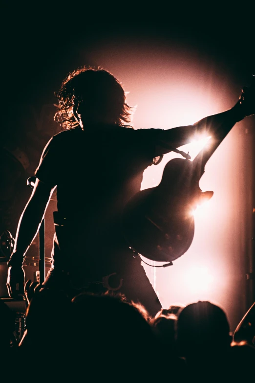 a musician playing a bass on stage while a concert is in the background