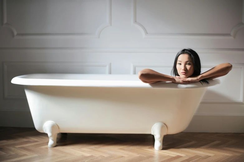 a woman poses in front of an ornate bathtub