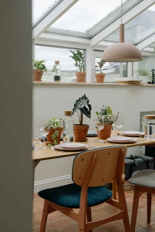 a wooden table surrounded by plants with windows