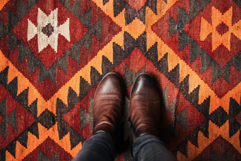 a man in brown shoes is standing on an old carpet