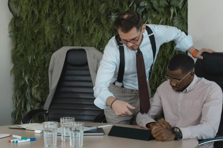 two men sitting at a table working on an item