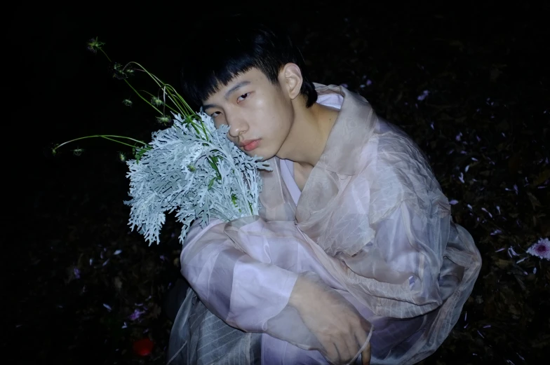 a young man holding a vase with white flowers