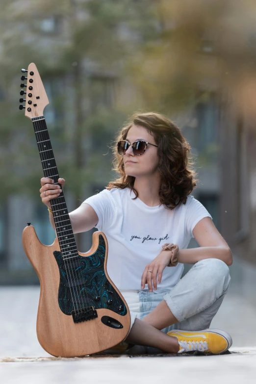 a woman is sitting on the ground with her guitar