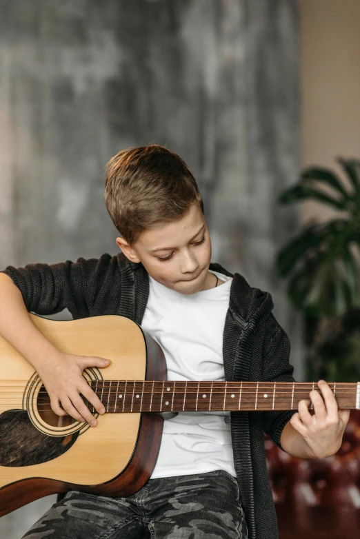 a boy holding an acoustic guitar in front of his face