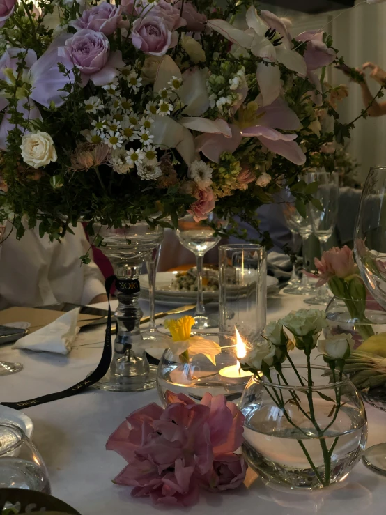 flower arrangement in center of table with glass vase and candles