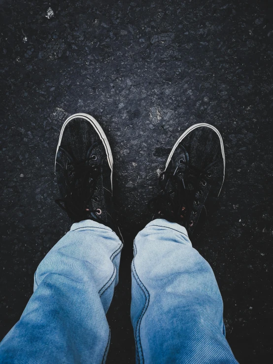 top down view of persons feet and jeans, on asphalt