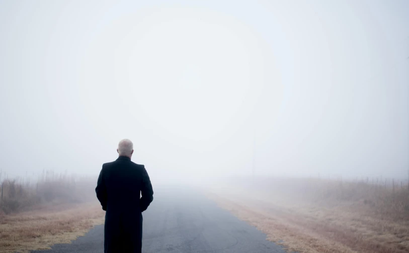 a man standing alone on a foggy road