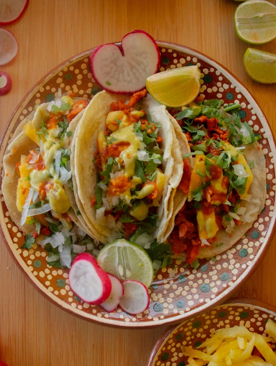 tacos on a plate next to a sliced lime and radishes