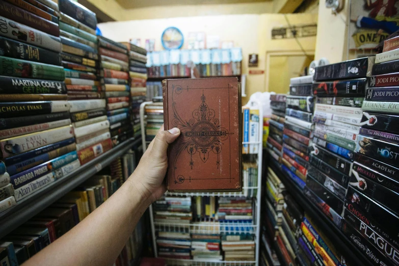 hand holding up book inside a bookstore store