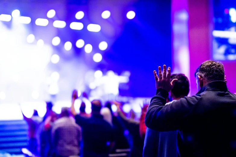 the audience at a conference applauds with their hands raised up in victory