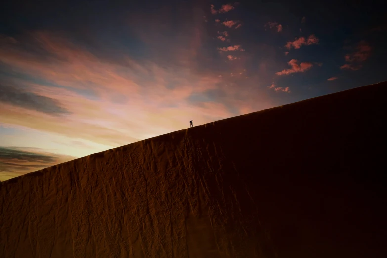 a lone person standing on top of a desert dune