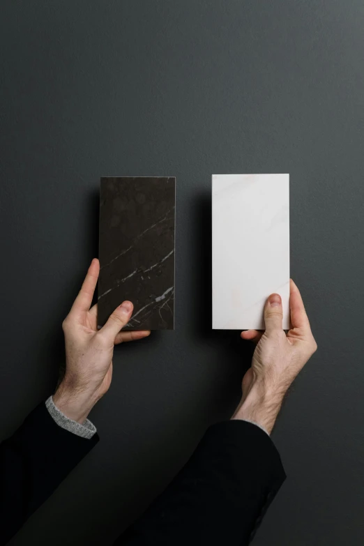 hands holding square black and white tiles