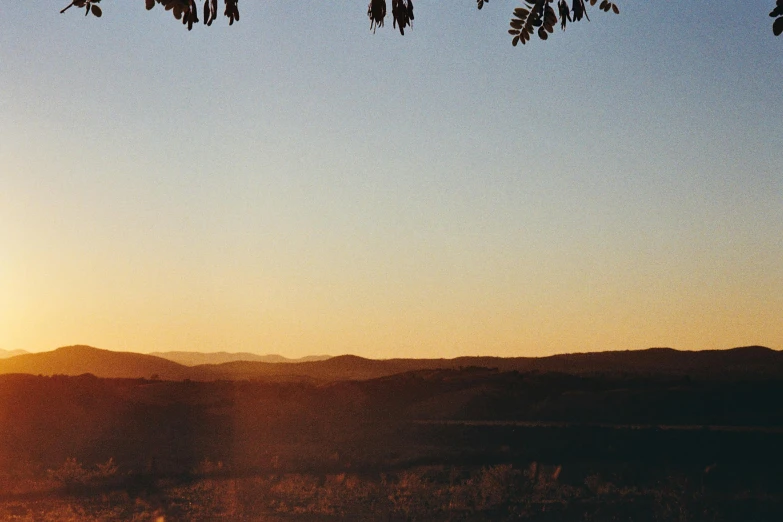 the sun is setting and some hills are in the background