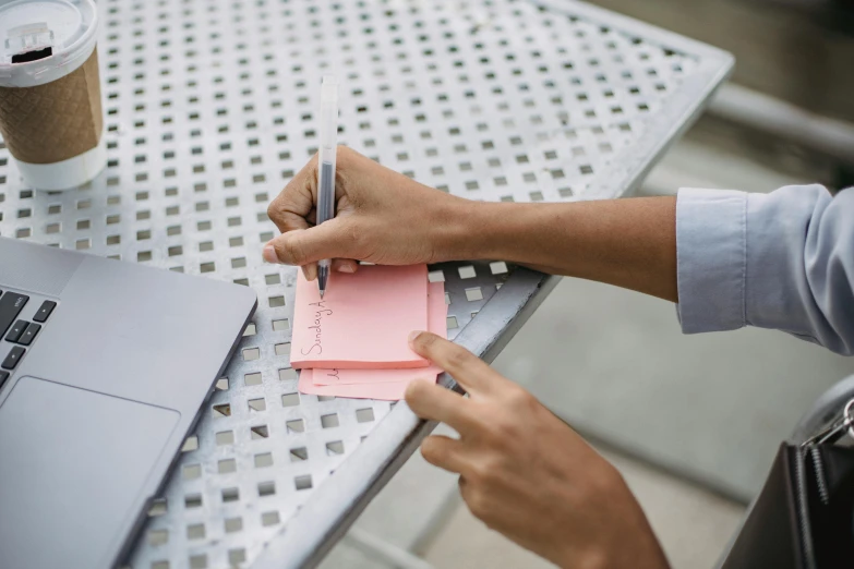 someone is writing a note on some pink paper