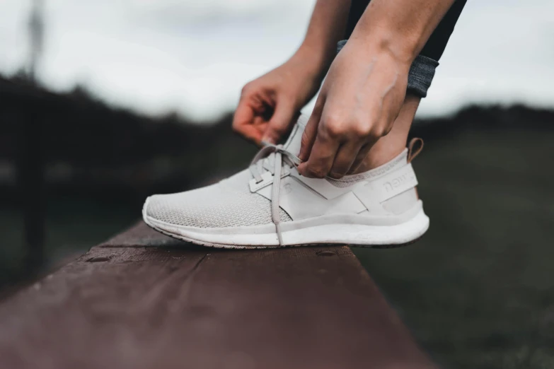 a person is tying their white sneakers with string