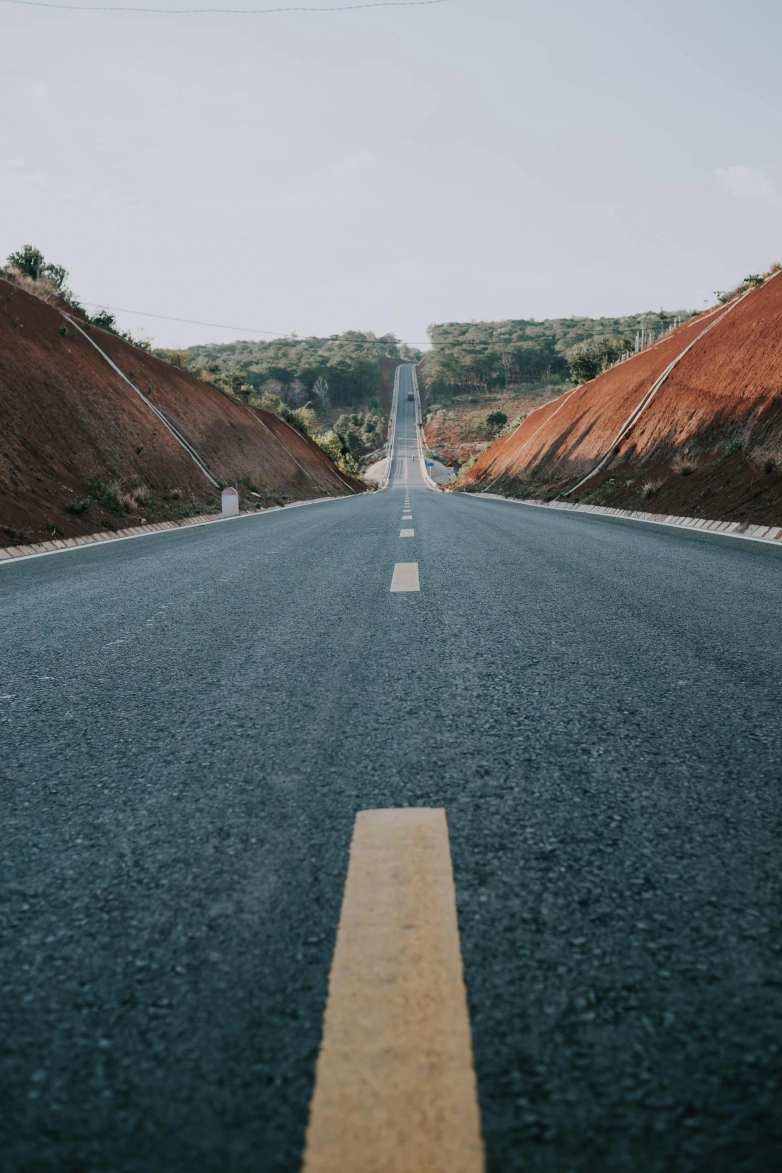 a long empty highway next to some brown hills