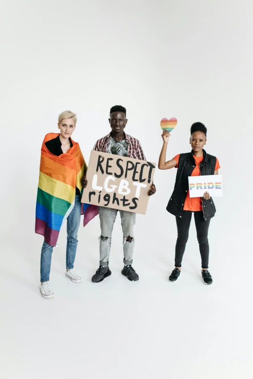 three people holding rainbow shirts, each of which is holding a paper sign