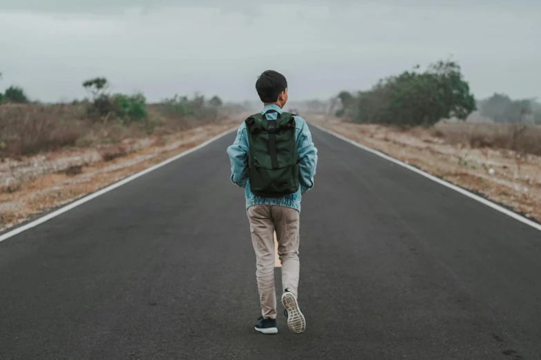 person wearing backpack on empty road in rural area