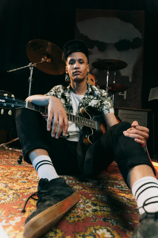 a man sitting on the ground holding his guitar