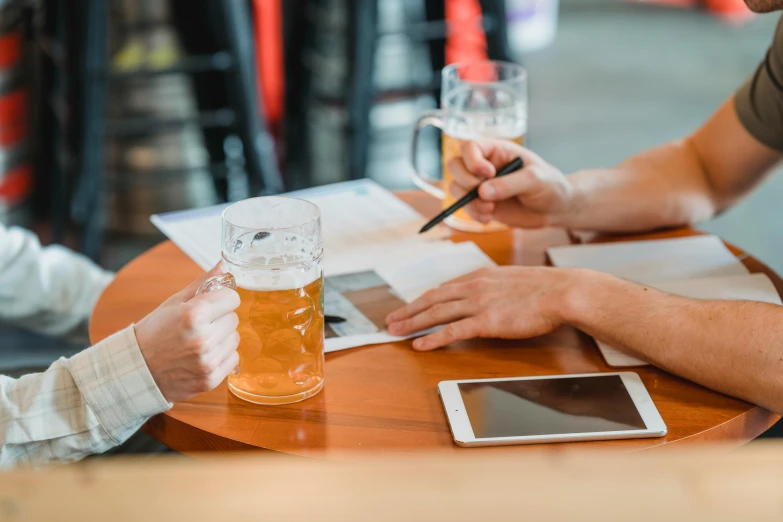 some people at a table with two beers and some papers