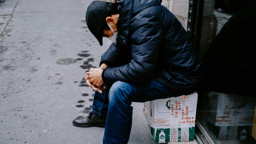 a man sitting on top of a window sill in front of a store