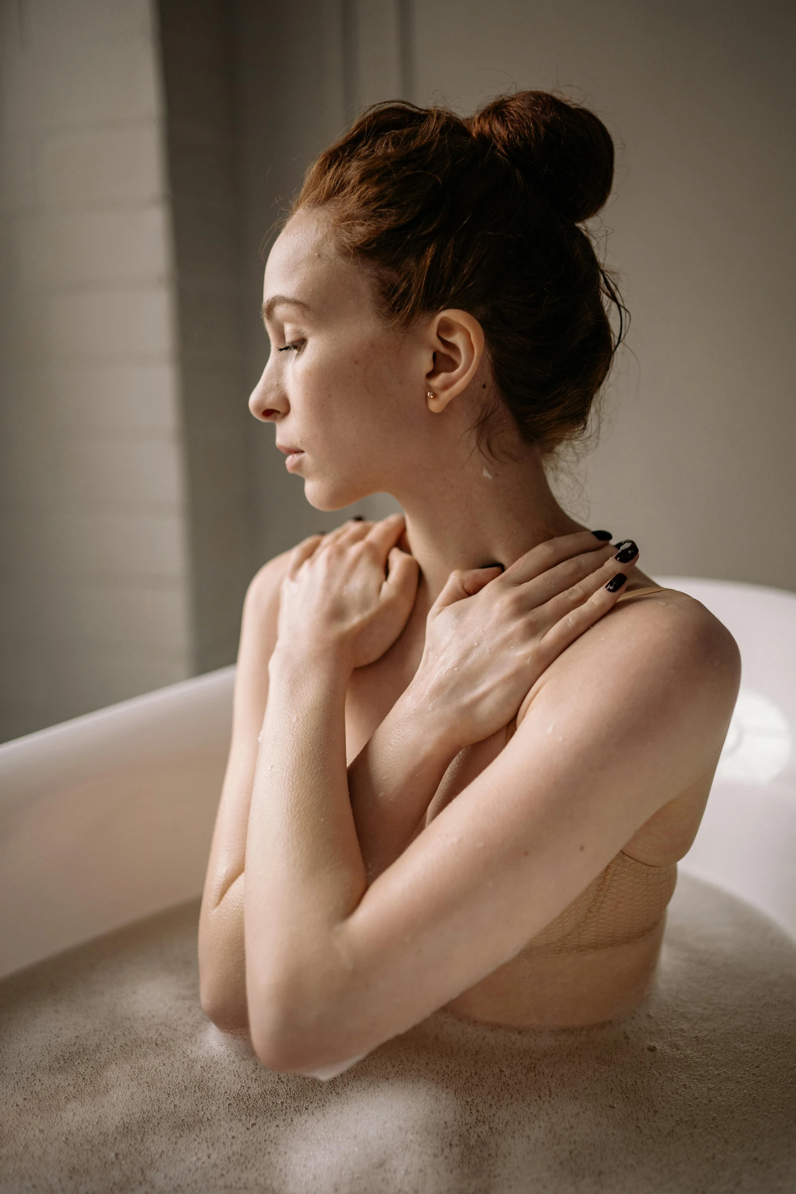 a girl with her hands on her chest sits in the bath