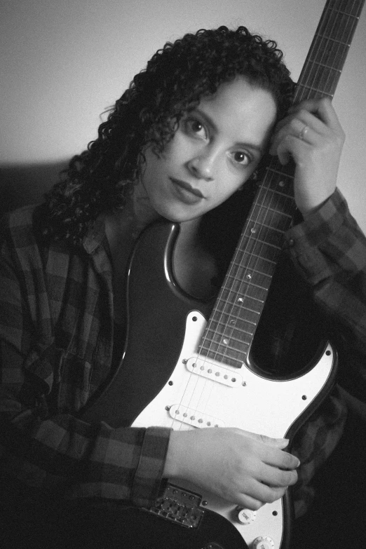 a woman with curly hair holding onto an electric guitar