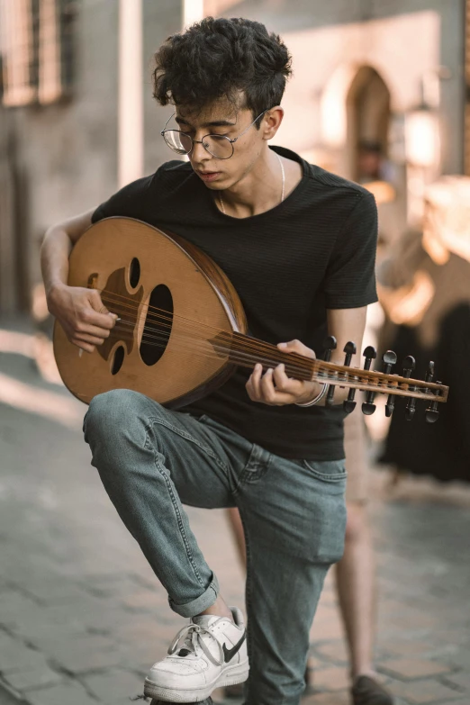 a boy holds an acoustic guitar while running down a street