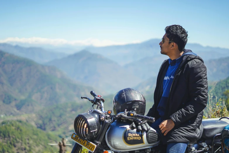 a man is sitting on his motorcycle looking over the mountains