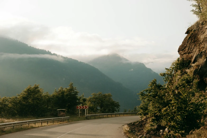 the scenic road in the mountains has a tall rock at one end