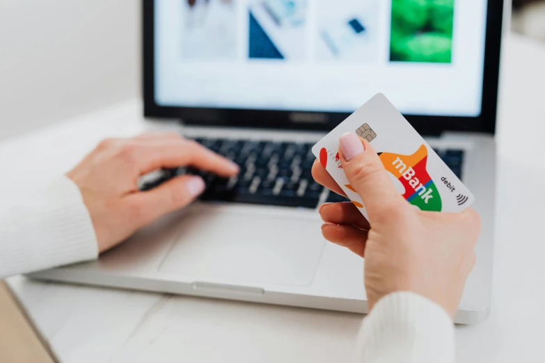 woman holding her credit card and typing on her laptop computer