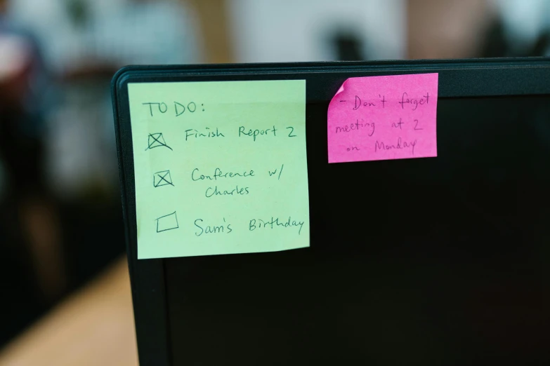 a computer monitor covered in note notes and a pen