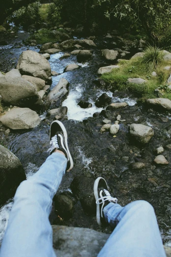 someone with their feet up in the air by a stream