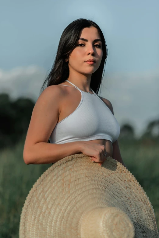 a young woman with a straw hat standing in a field