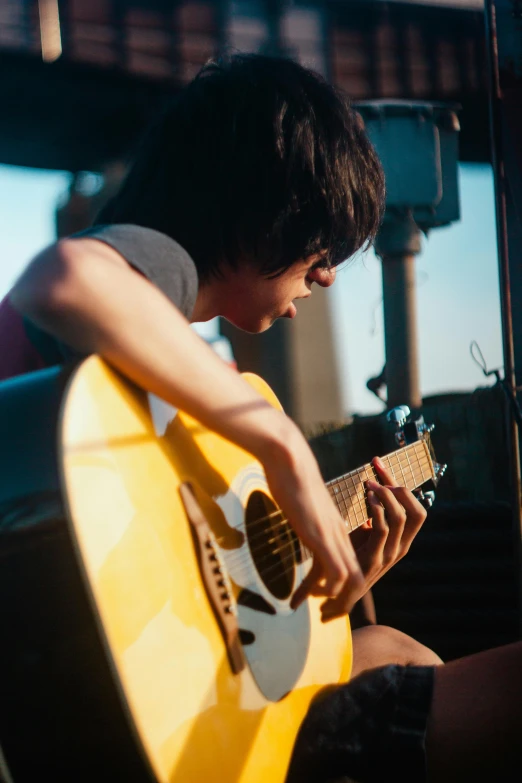 the boy is playing his guitar near the building