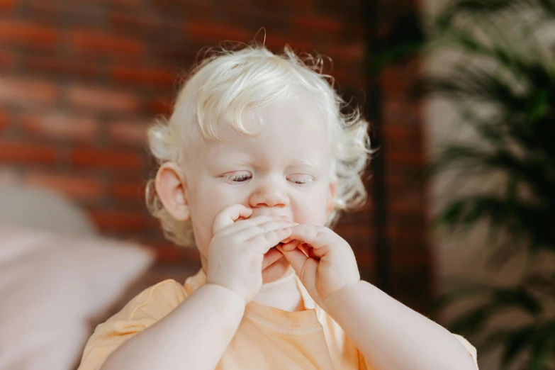 a close up of a child with blonde hair wearing an orange shirt