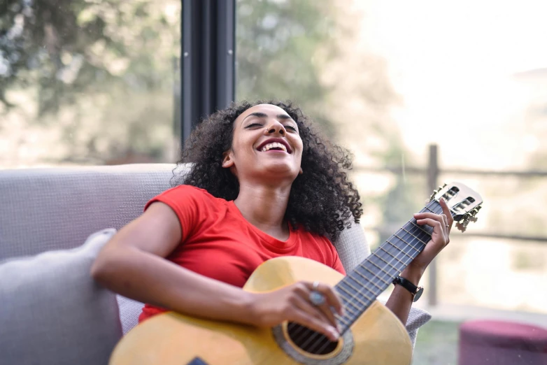 a young woman sitting on a couch holding a guitar