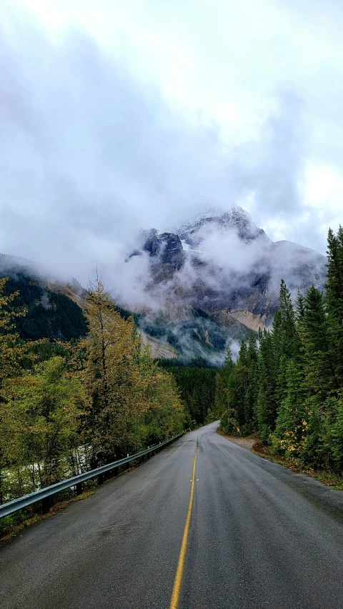 road in the distance with clouds and mountains in the background