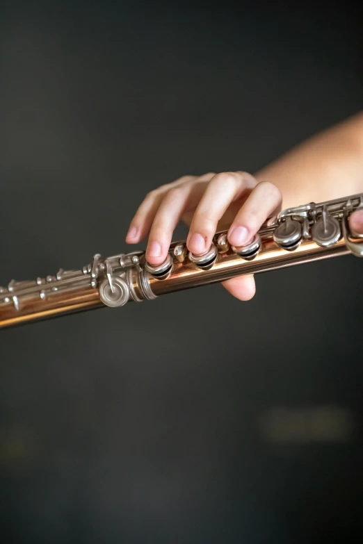 person playing a flute with fingers on a black background