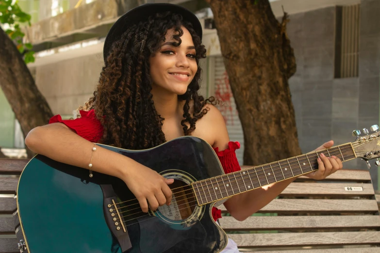 a young lady sitting on a park bench playing a guitar