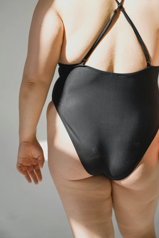 the backside view of a woman wearing a black swimsuit