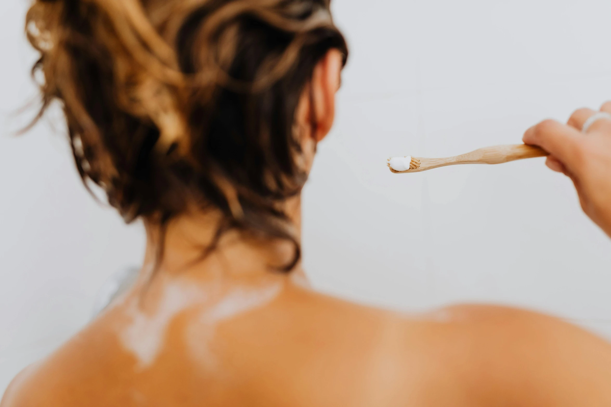 a woman uses a toothbrush on her back