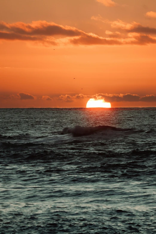 a sunset behind a body of water with a boat out in the distance