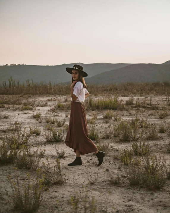 a woman with a hat walking in the desert