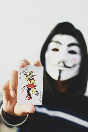 a person with a mask on and holding a card