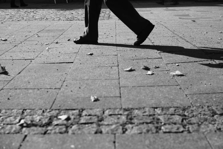 black and white pograph of a person walking down a brick sidewalk