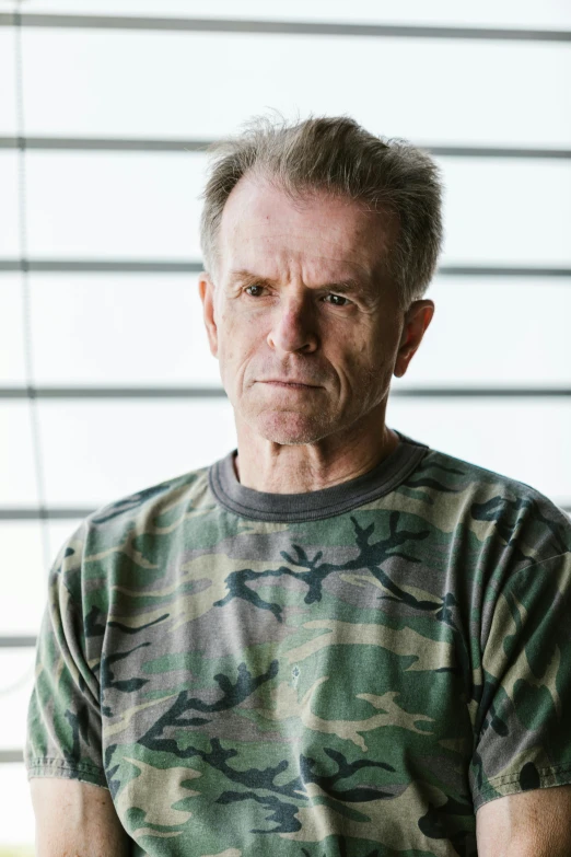 a man sitting in front of a window next to blinds