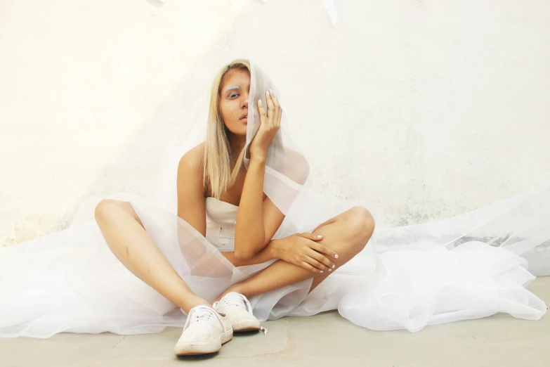 a woman sitting on the floor posing in her wedding attire