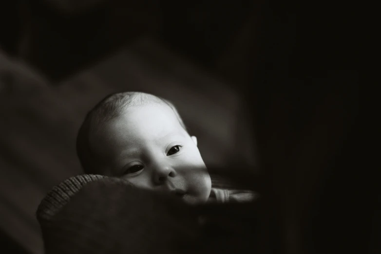 a baby wearing a sweater looks off into the distance